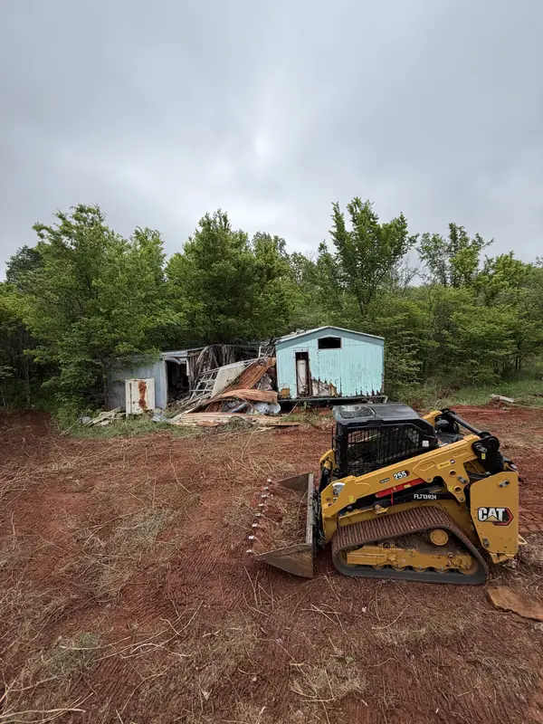 CAT skid steer on shed demo site — teardown underway