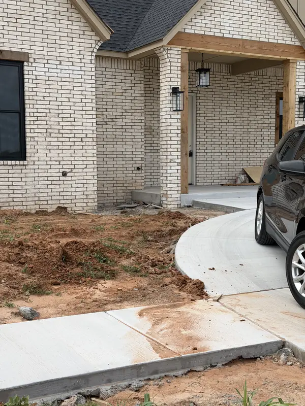 New home front with a curved concrete drive and graded yard